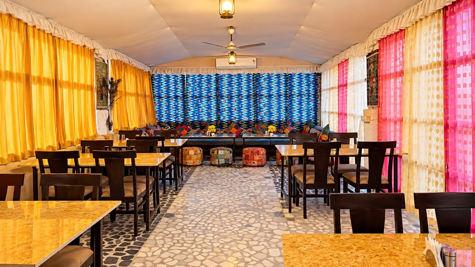Un restaurante con una pared estampada, varias mesas y sillas, y un piso de baldosas.