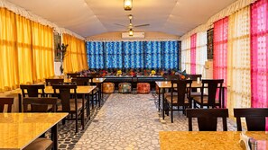 A restaurant with a patterned wall, multiple tables and chairs, and a tiled floor. - Hotel Swan Haveli (Jaisalmer)