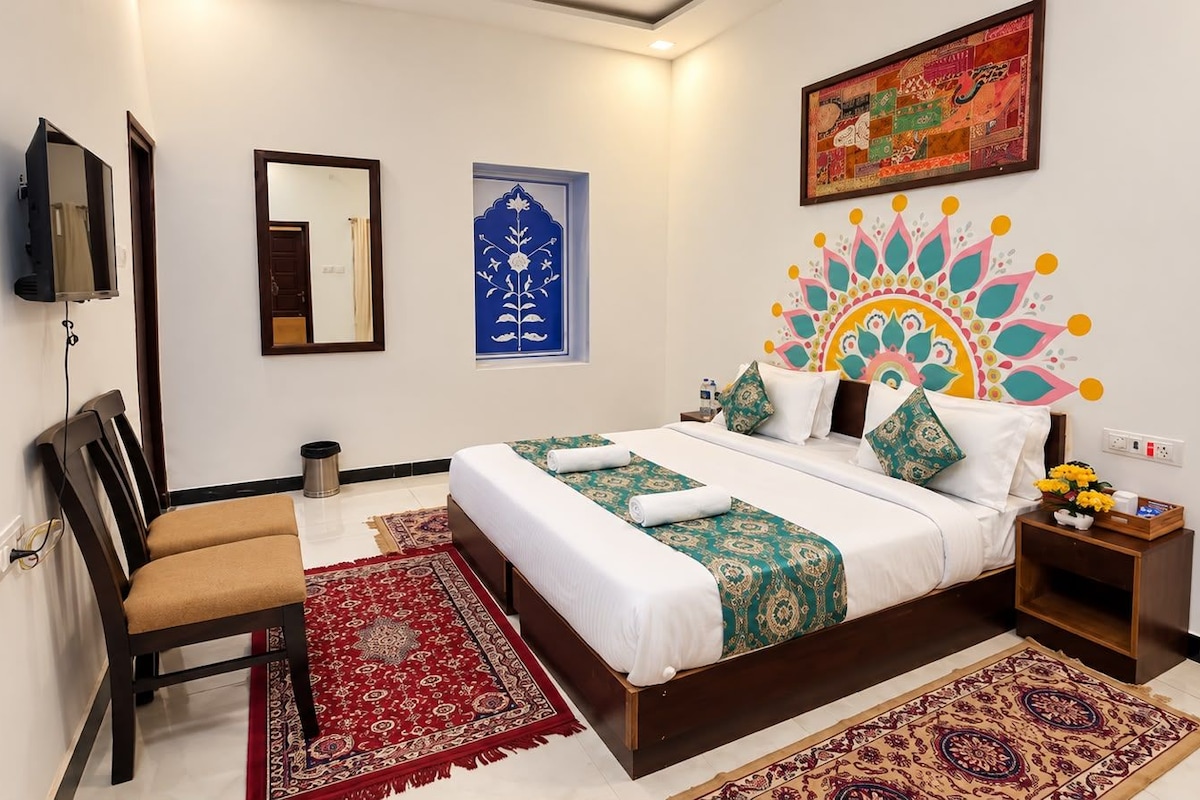 A hotel room with a bed, a chair, a nightstand, a TV, and decorative wall art.
