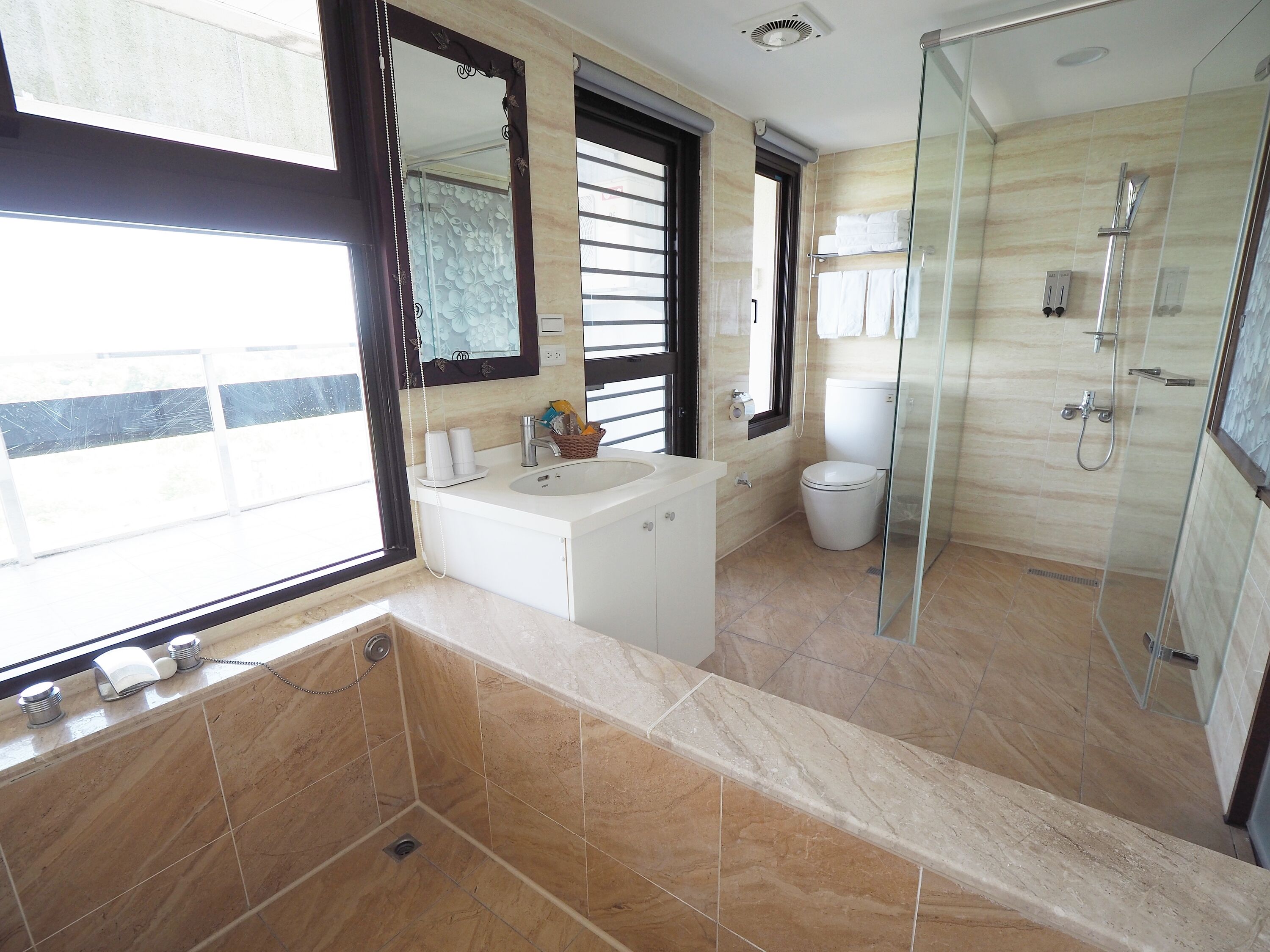 Casa de banho moderna com banheira, sanita e área de duche com divisória de vidro.