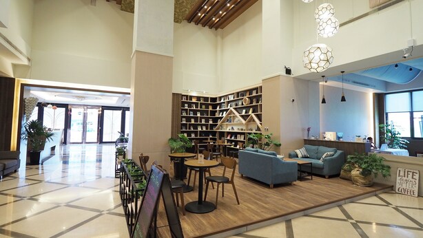 A spacious lobby with a central seating area, a large bookshelf, and a coffee station. - Kailan Hotel (Toucheng)