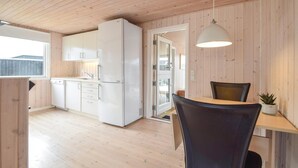 Une cuisine compacte avec des meubles blancs, un réfrigérateur et un coin repas comprenant une table et des chaises.