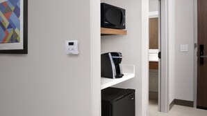 Eine moderne Küche mit Mikrowelle, Kaffeemaschine und Kühlschrank auf einem weißen Regal.