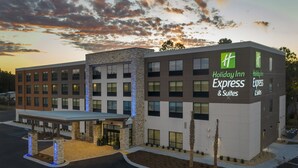 Ein Holiday Inn Express & Suites Gebäude im modernen Design, mit überdachter Zufahrt und einer angelegten Fläche mit Palmen.