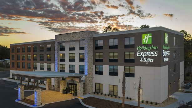 A Holiday Inn Express & Suites building with a modern design, featuring a covered entrance and a landscaped area with palm trees. - Holiday Inn Express & Suites Kingsland I-95-Naval Base Area by IHG (Kingsland)