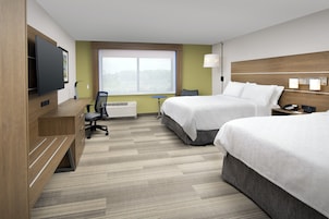 Habitación de hotel con dos camas, un escritorio, una silla, un televisor y una ventana con vistas.