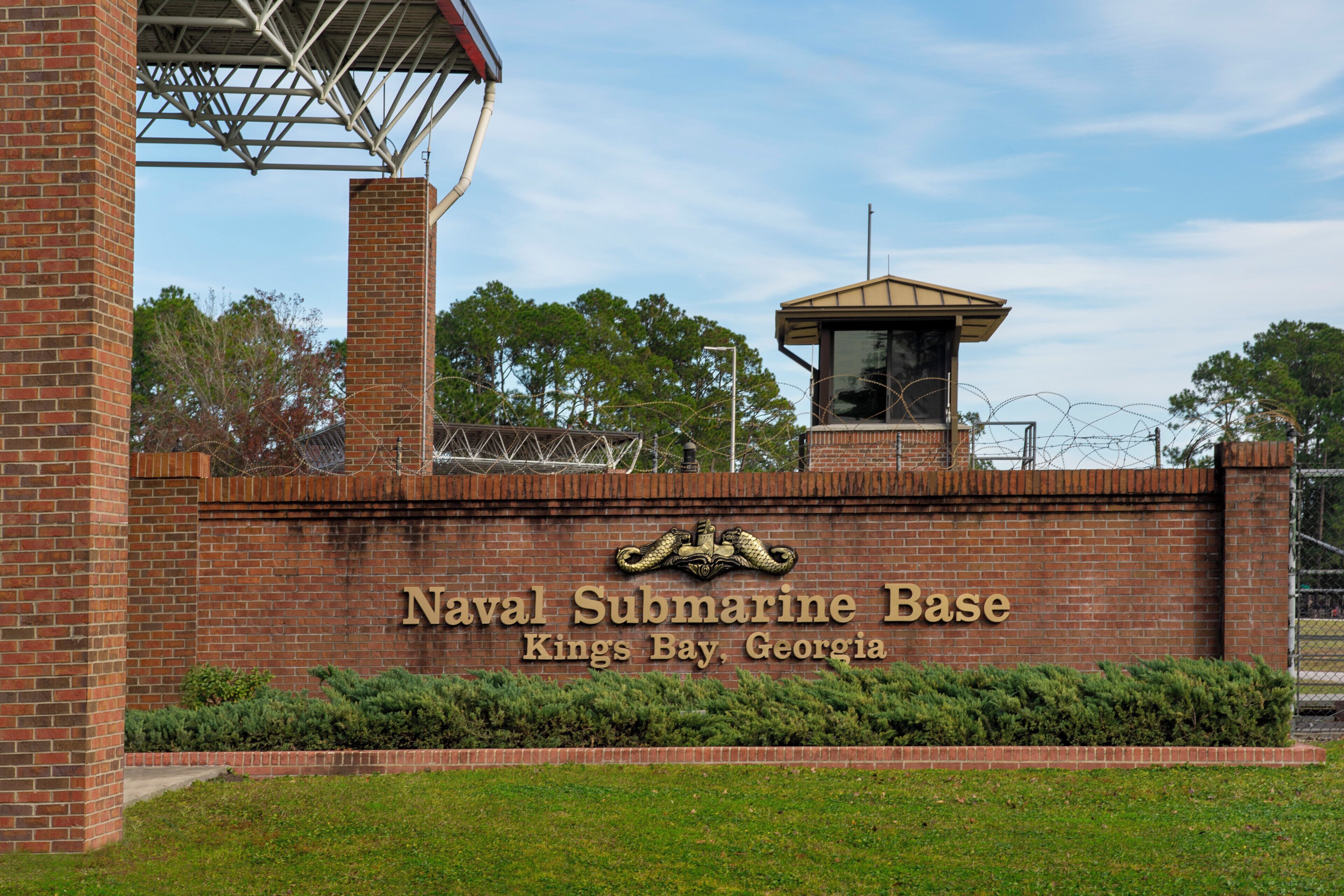 A brick wall with the text 'Naval Submarine Base Kings Bay, Georgia' and a small tower structure.