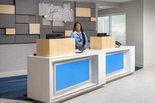 Un mostrador de recepción de diseño moderno, con un gran panel azul y detalles de madera.