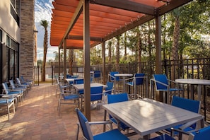 An outdoor patio with tables and chairs, a stone building, and a wooden pergola. - Holiday Inn Express & Suites Kingsland I-95-Naval Base Area by IHG (Kingsland)