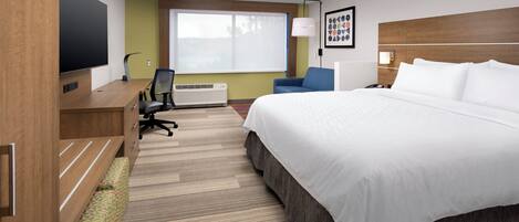 Una habitación de hotel con cama, escritorio, silla y televisor.