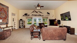 A living room with a fireplace, a television, and a large window. - Spacious Private Lodge with Mountain Views (Leavenworth)