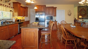 A spacious kitchen with wooden cabinets, a stainless steel refrigerator, and a dining area with wooden chairs and a table. - Spacious Private Lodge with Mountain Views (Leavenworth)