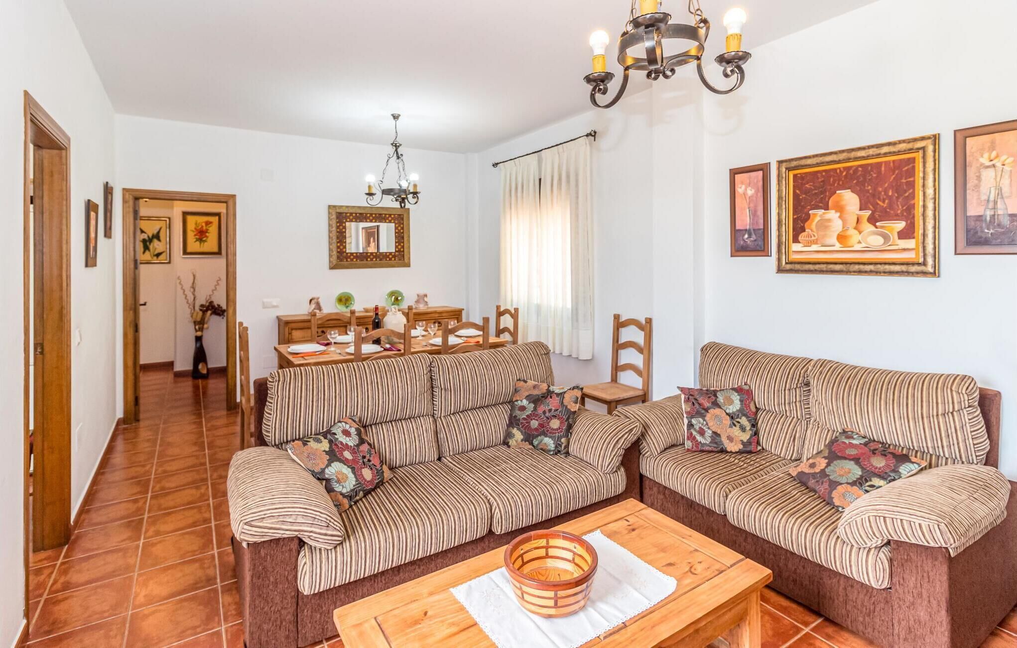 A living room with striped sofas, a wooden coffee table, and a dining area with a table set for four.