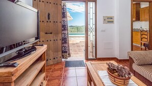 A living room with a TV, wooden furniture, a sliding glass door leading to an outdoor patio, and a view of the landscape. - Amazing home in Periana (Periana)