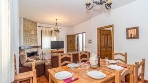A dining area with a wooden table set for four, a television, and a stone wall. - Amazing home in Periana (Periana)