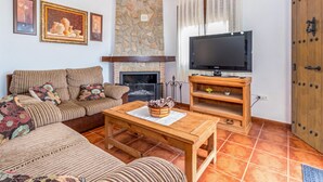 A cozy living room with a sofa, a coffee table, a fireplace, a television, and a stone wall. - Amazing home in Periana (Periana)