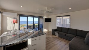 Ett modernt kök med en bänkskiva i marmor, en inbyggd ugn och en matplats med utsikt över havet.