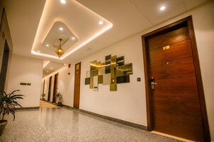 A modern hotel lobby with a polished granite floor, a geometric wall art installation, and a wooden door with a sign.