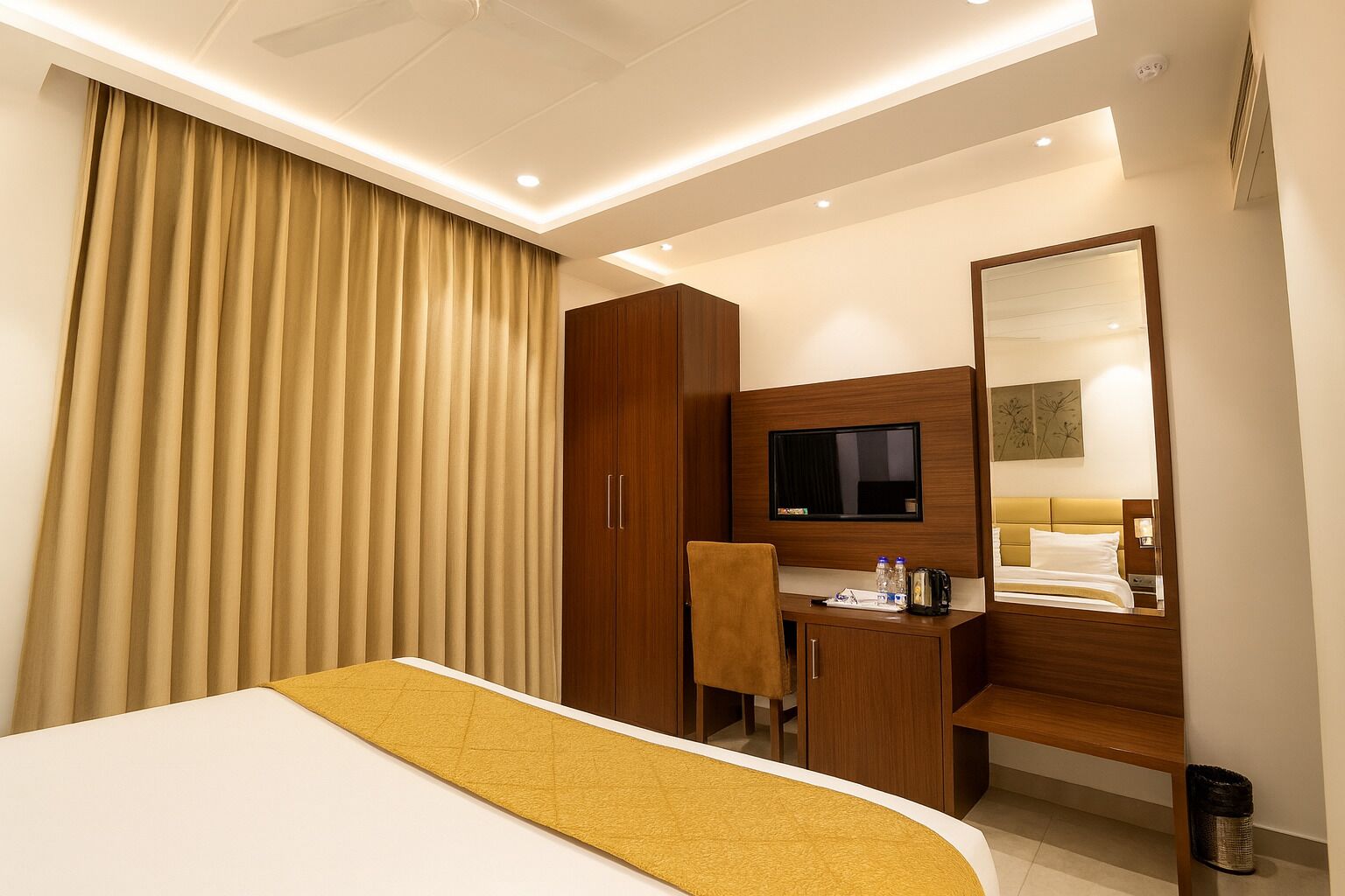 A hotel room with a bed, a desk, a chair, a TV, and a wardrobe.