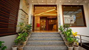 A hotel entrance with a staircase, potted plants, and a modern interior design. - HOTEL TEN SQUARE - 5 Minutes from The Taj Mahal (Agra)