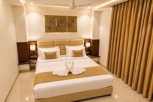 A hotel room with a large bed, a ceiling fan, a wall-mounted artwork, and a curtain.