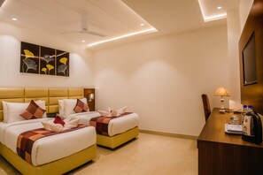 Ein Hotelzimmer mit zwei Betten, einem Schreibtisch, einem Fernseher und einem Deckenventilator.
