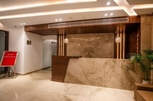 A reception area with a marble reception desk, wooden paneling, and a red sign.