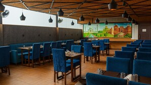 A restaurant with blue booths and tables, wooden floors, and pendant lighting. - HOTEL TEN SQUARE - 5 Minutes from The Taj Mahal (Agra)
