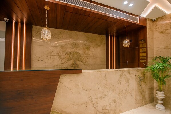 A reception area with a marble counter, wooden paneling, and hanging crystal chandeliers.