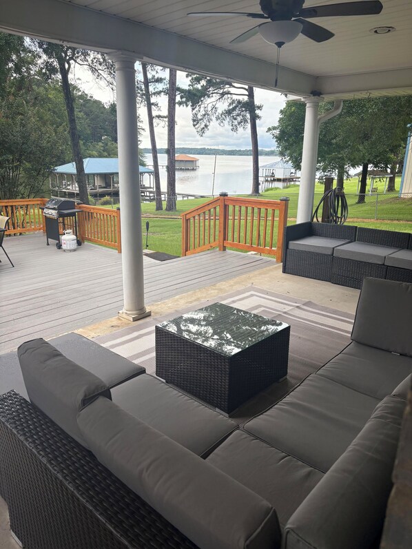 A covered outdoor seating area with a view of a lake, a grill, and a gazebo. - Spacious Lakefront Retreat - Sleeps 10 - Kayaks, Fishing, & Game Room. (Bullard)
