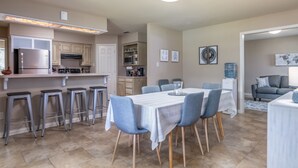 Une cuisine moderne dotée d’un îlot central, de tabourets de bar et d’un coin repas avec une table et des chaises.