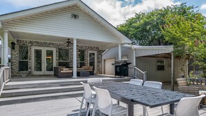 Une terrasse extérieure couverte, équipée d’une table et de chaises, d’un barbecue et d’un coin salon avec des canapés et une table à manger.