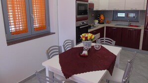Une cuisine compacte avec un coin repas, comprenant une table avec des chaises, un vase de fleurs et un four à micro-ondes.