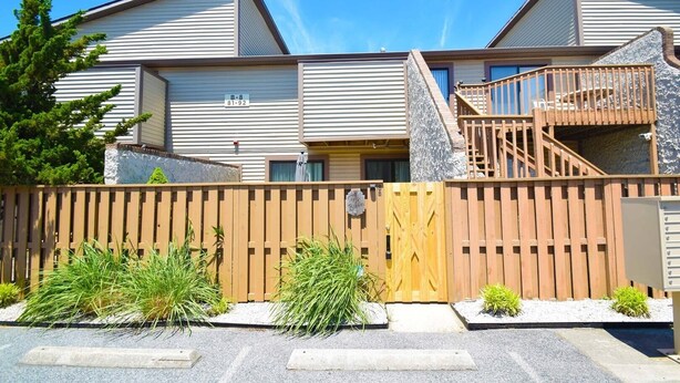 A two-story building with a wooden fence, a stone staircase, and a sign indicating unit B-8.
