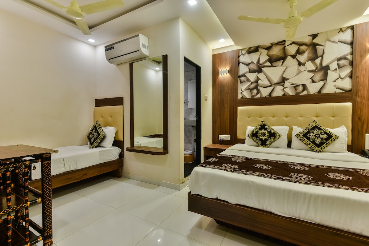 A hotel room with two beds, a mirror, a ceiling fan, and a wall-mounted air conditioner.