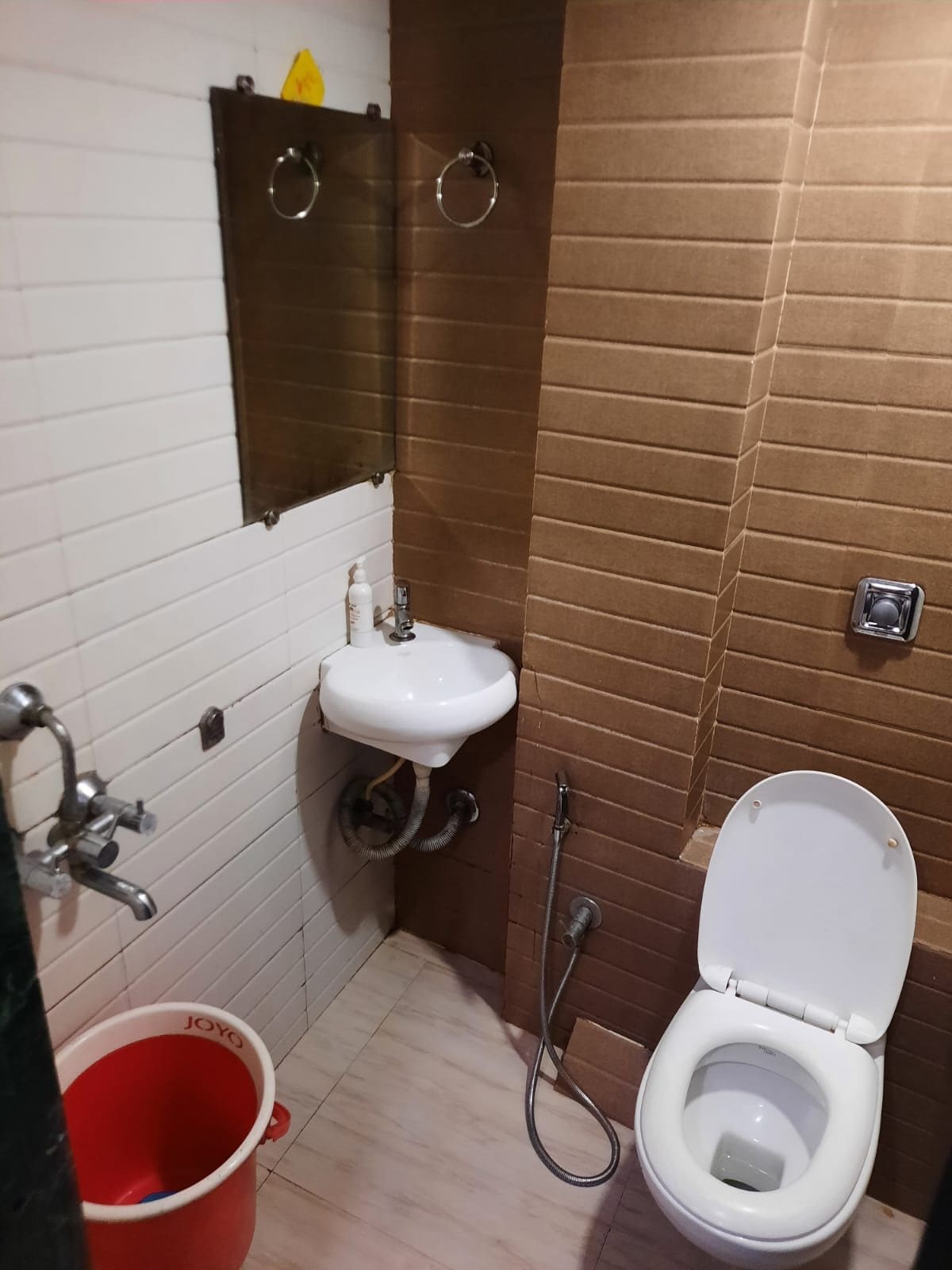 A bathroom with a white sink, a toilet, and a red bucket.
