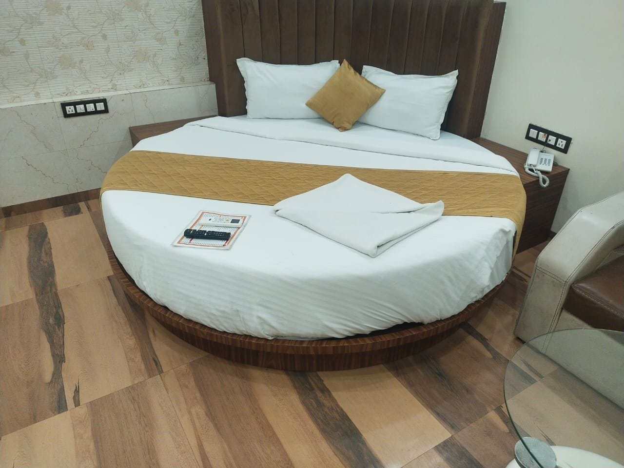 A hotel room with a round bed, a bedside telephone, and a small table.