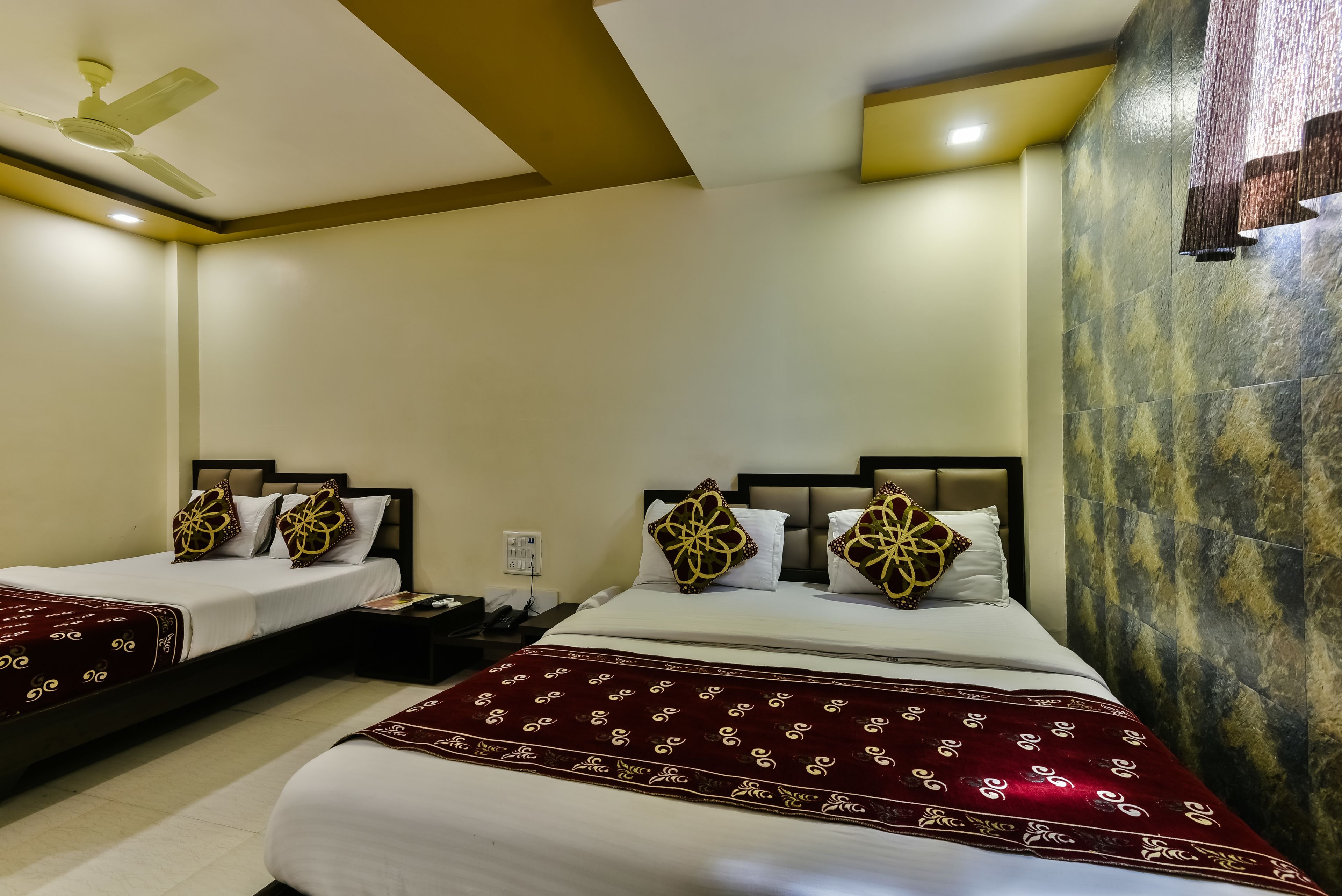 A hotel room with two beds, each with a red and white bedspread, and a ceiling fan.