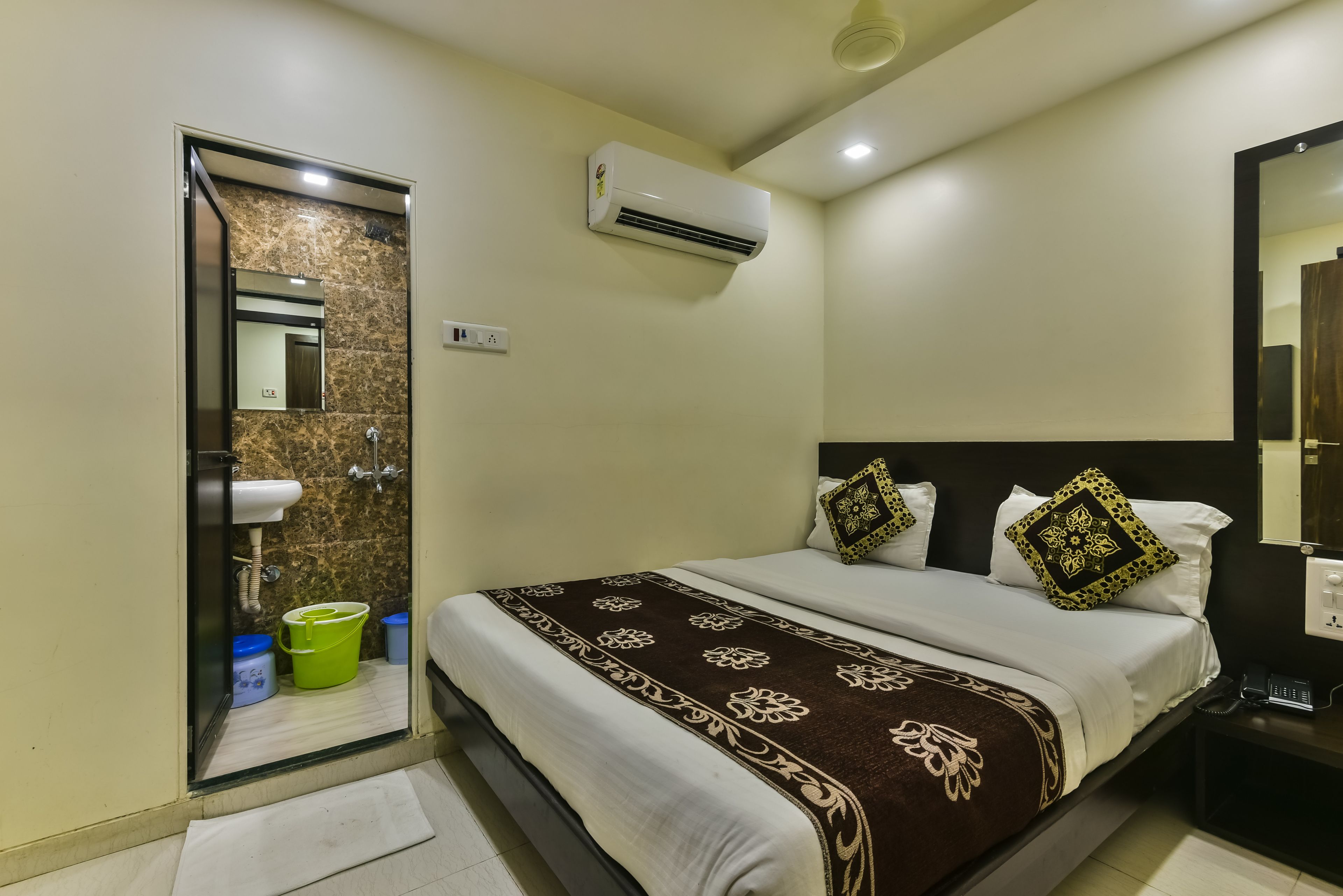 A hotel room with a bed, a bathroom, and an air conditioning unit.