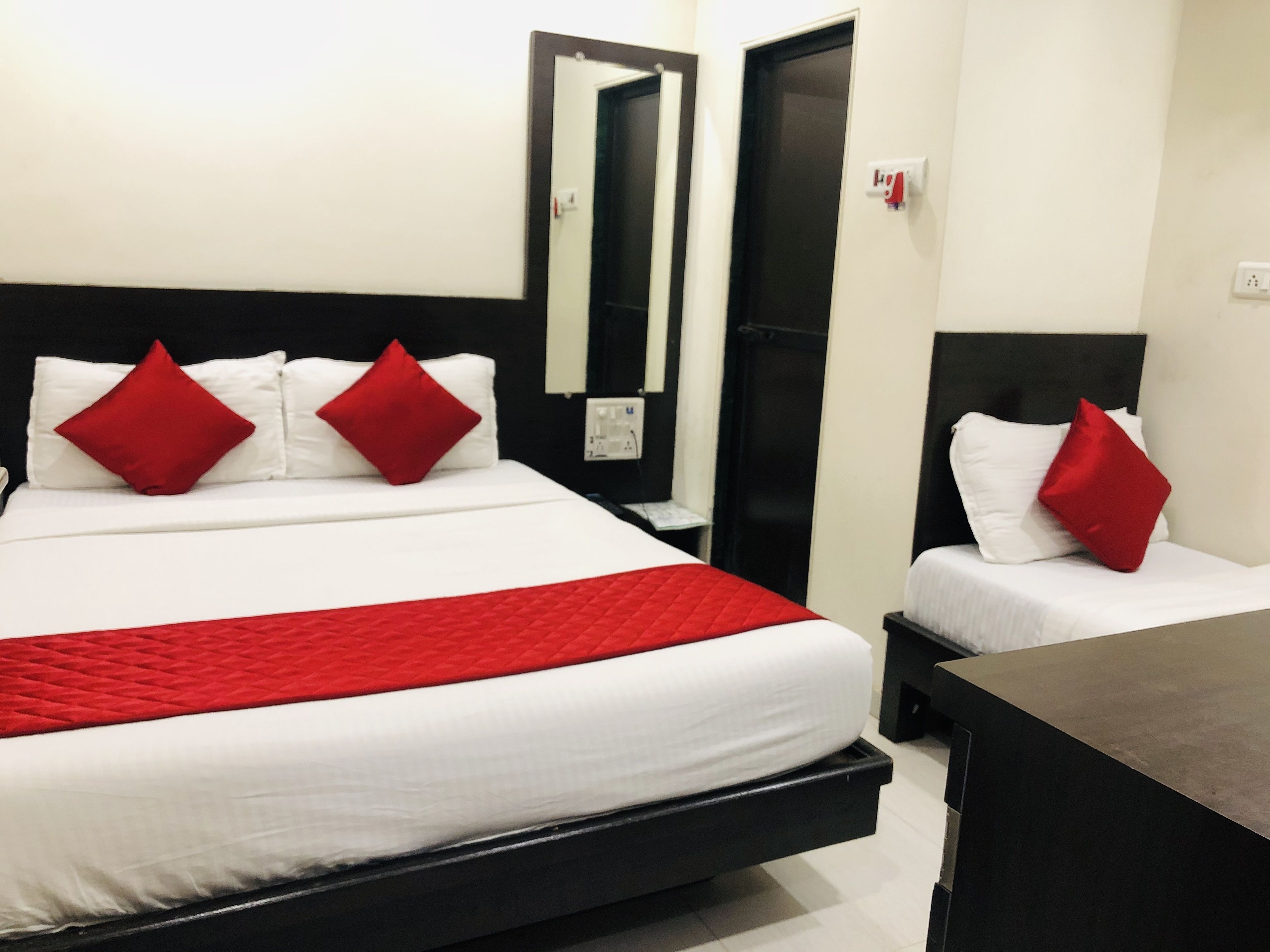 A hotel room with a large bed, two bedside tables, a dresser, a mirror, and a door.