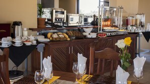 A breakfast buffet with various food items, a coffee station, and a seating area with tables and chairs. - Callies Game Lodge Safaris (Tsumeb)