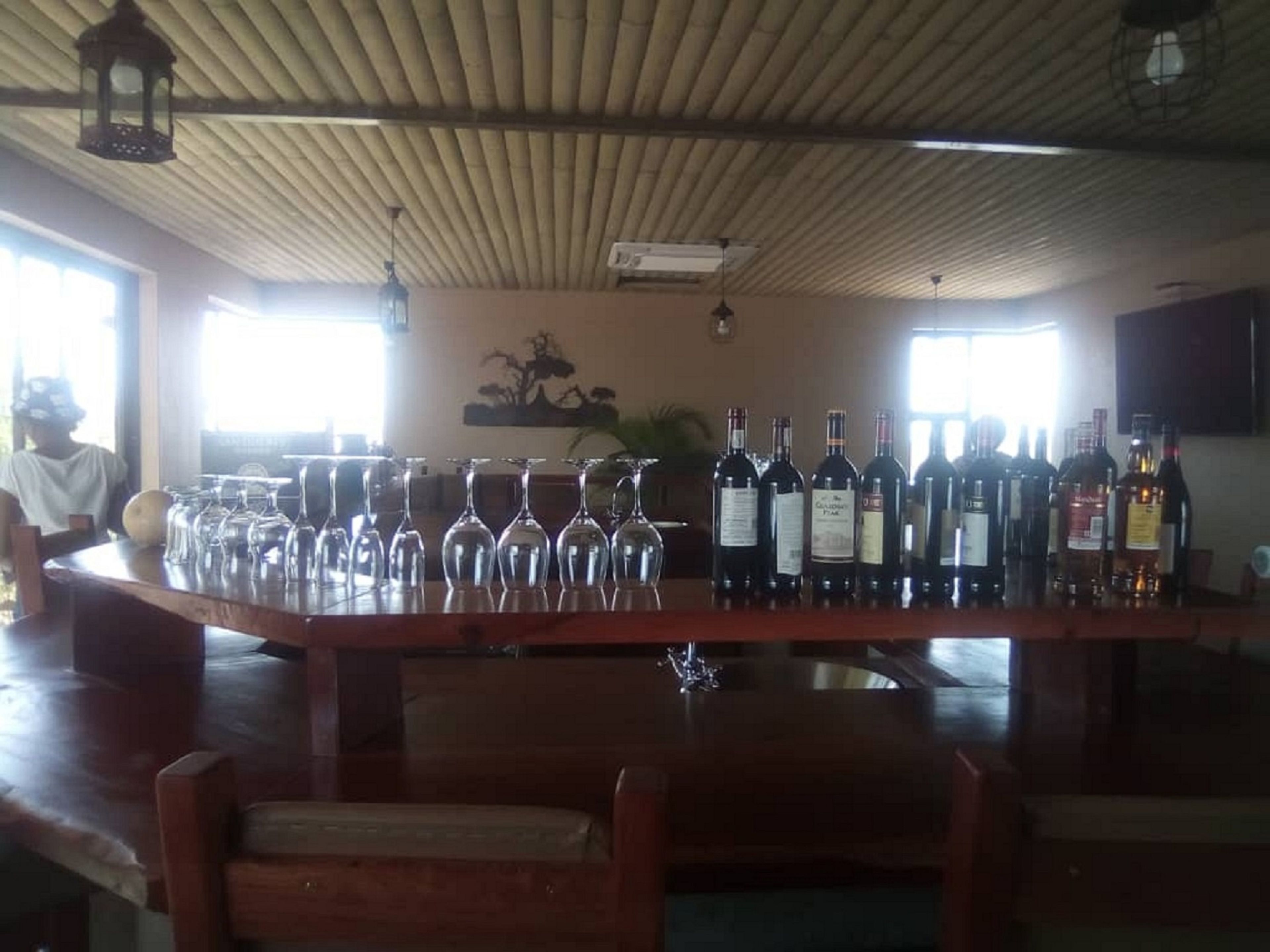 Un espace bar avec un comptoir en bois, des bouteilles de vin et des verres à vin.