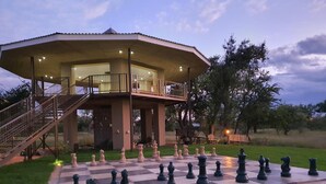 A large outdoor chessboard set up on a patio with a building in the background. - Callies Game Lodge Safaris (Tsumeb)