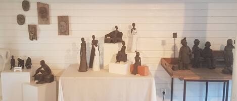 Verschillende sculpturen staan op een tafel voor een witte muur.