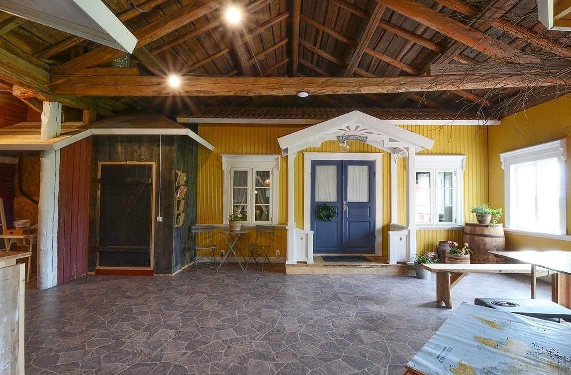 A spacious room with a stone floor, wooden beams on the ceiling, and a yellow and blue color scheme.