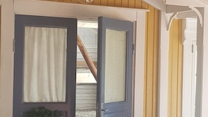 A wooden door with a wreath, a sign above it, and a stone floor. - Nygården Bed&Breakfast (Harmanger)