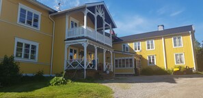 A yellow building with a balcony and a covered porch. - Nygården Bed&Breakfast (Harmanger)