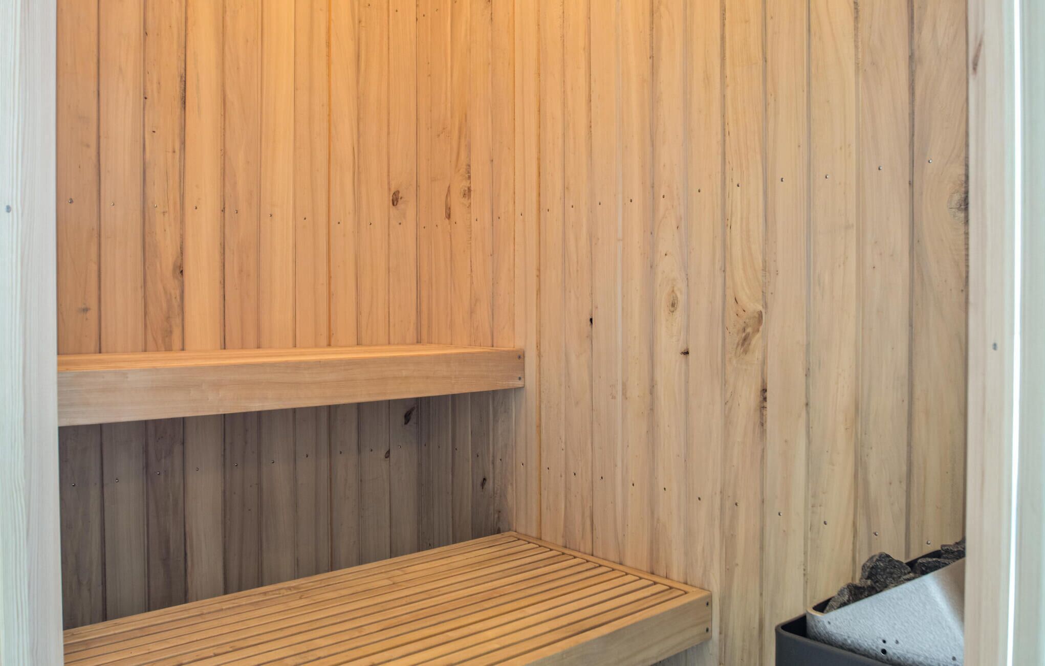 Una sauna in legno con due panche e una panca a terra.