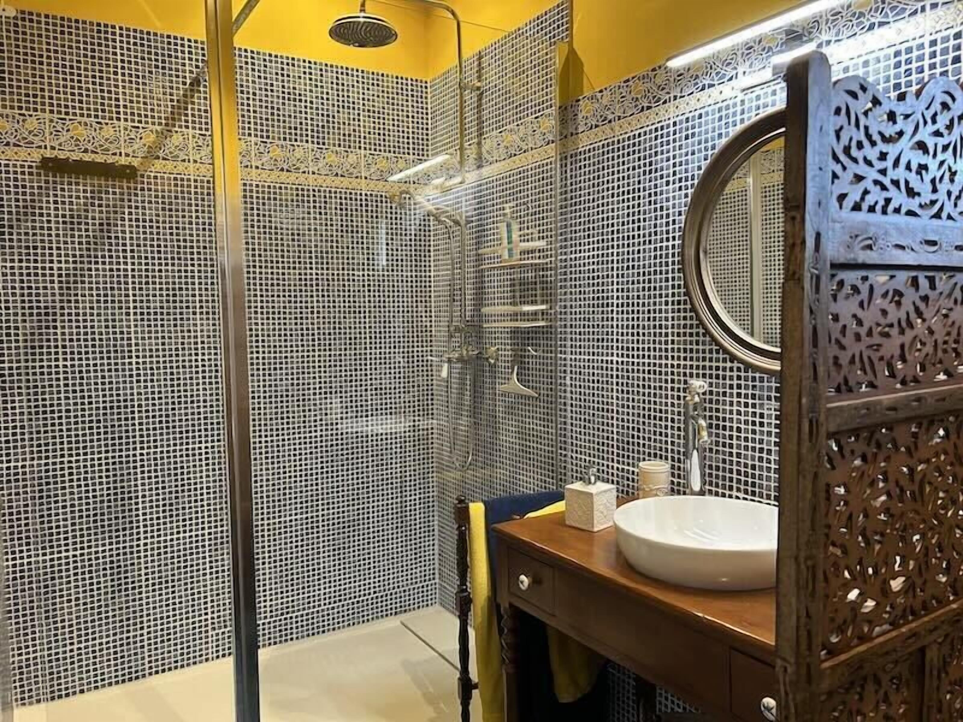 Un bagno con doccia, lavandino e specchio.