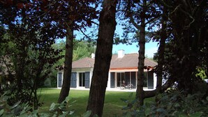 Une maison avec un toit en tuiles, un vélo garé dans l’allée et une pelouse bien entretenue.